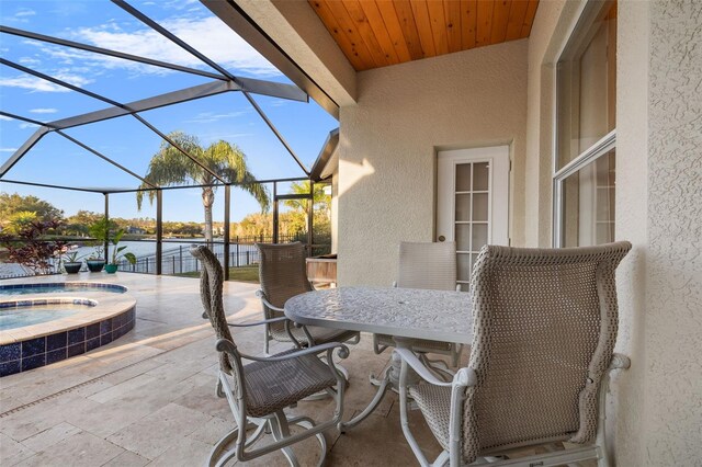 view of patio / terrace with an in ground hot tub, a water view, and a lanai