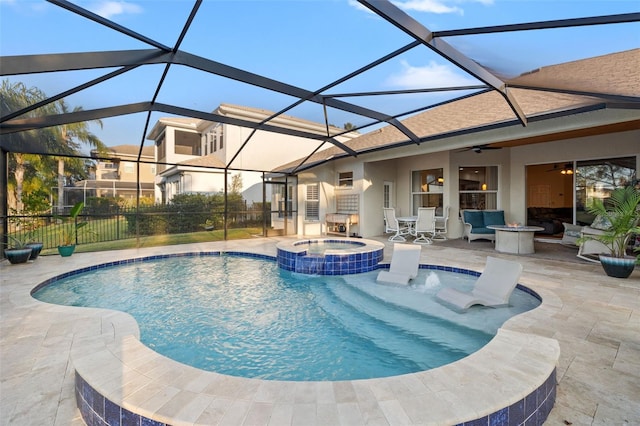 view of pool with an in ground hot tub, ceiling fan, a patio, and glass enclosure