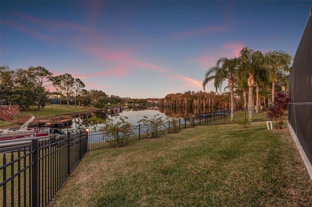 yard at dusk featuring a water view