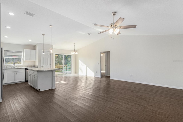 kitchen featuring a center island, light stone counters, pendant lighting, lofted ceiling, and white cabinets