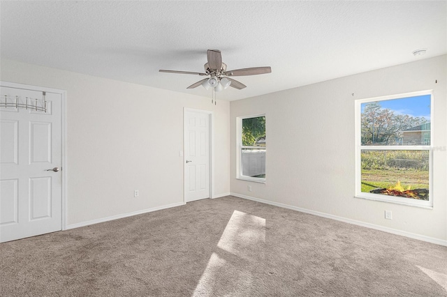 unfurnished room with a textured ceiling, carpet floors, and ceiling fan