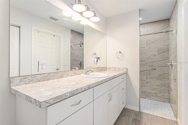 bathroom with tiled shower and vanity