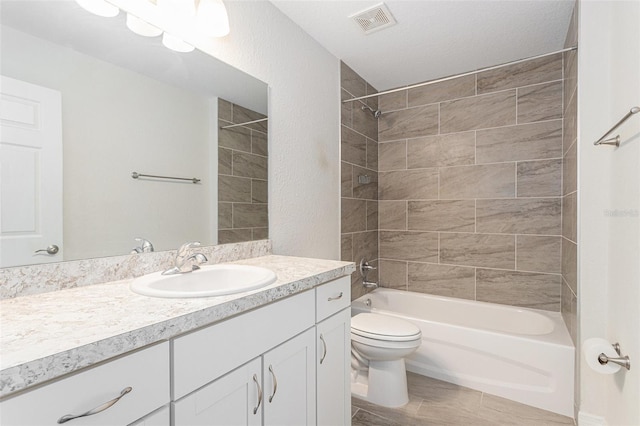 full bathroom with tile patterned floors, vanity, a textured ceiling, toilet, and tiled shower / bath