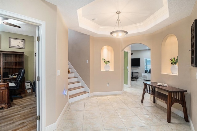 entryway featuring a raised ceiling and light tile patterned floors