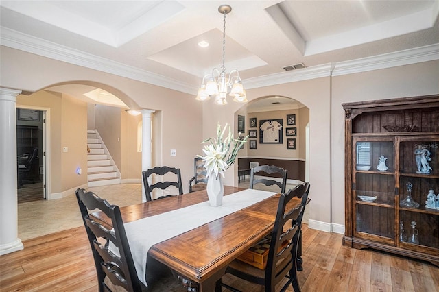 dining room featuring light hardwood / wood-style floors, a raised ceiling, crown molding, and a chandelier