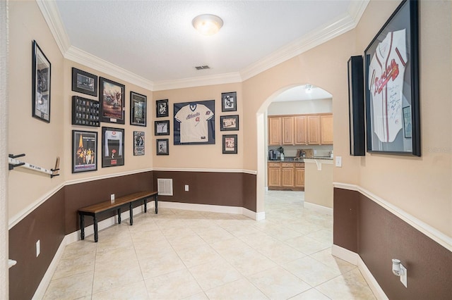 corridor featuring a textured ceiling, light tile patterned floors, and crown molding