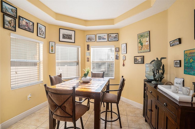 dining area with a raised ceiling and light tile patterned floors