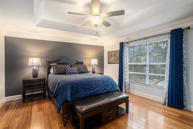 bedroom with hardwood / wood-style flooring, a raised ceiling, ceiling fan, and ornamental molding