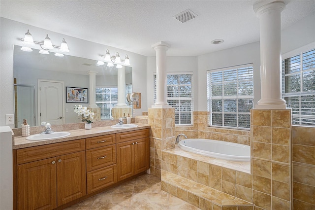 bathroom with vanity, decorative columns, tile patterned floors, and a relaxing tiled tub