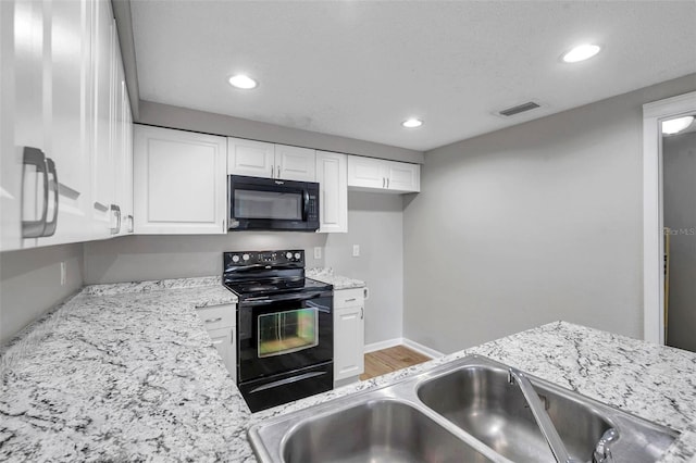 kitchen featuring black appliances, light stone countertops, hardwood / wood-style flooring, white cabinets, and sink