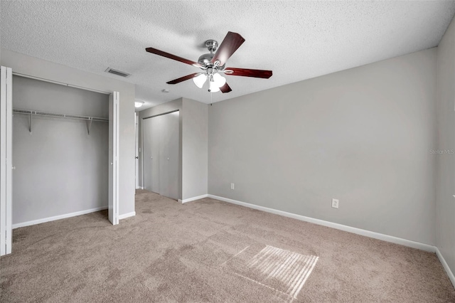 unfurnished bedroom with a closet, light carpet, ceiling fan, and a textured ceiling