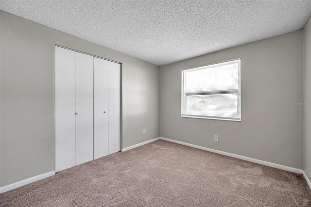 unfurnished bedroom with a textured ceiling, a closet, and light carpet