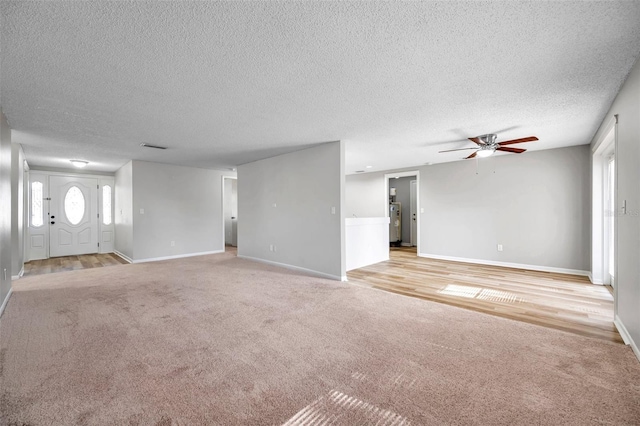 unfurnished living room with water heater, a textured ceiling, ceiling fan, and light carpet