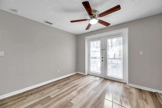 spare room featuring a textured ceiling, light hardwood / wood-style flooring, french doors, and ceiling fan