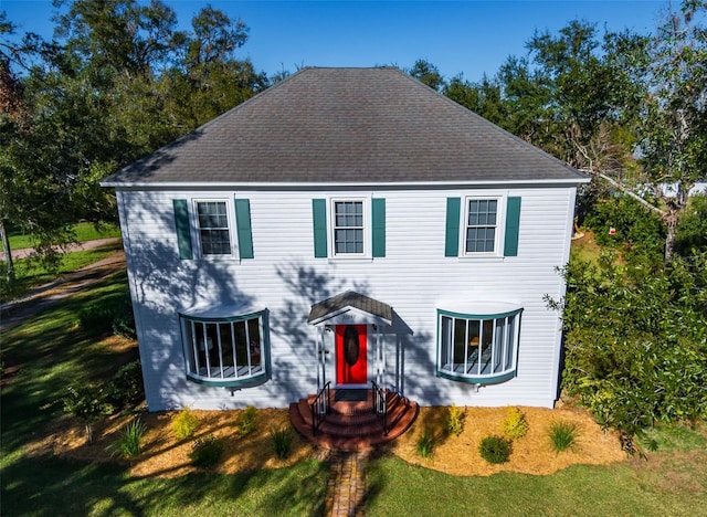 colonial-style house featuring a front lawn