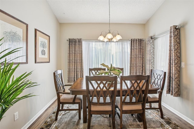 dining space featuring a textured ceiling, a chandelier, and dark hardwood / wood-style floors