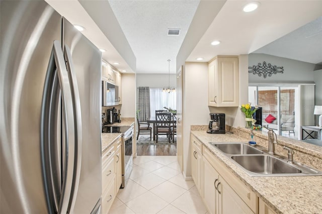 kitchen featuring light tile patterned flooring, pendant lighting, stainless steel appliances, sink, and vaulted ceiling