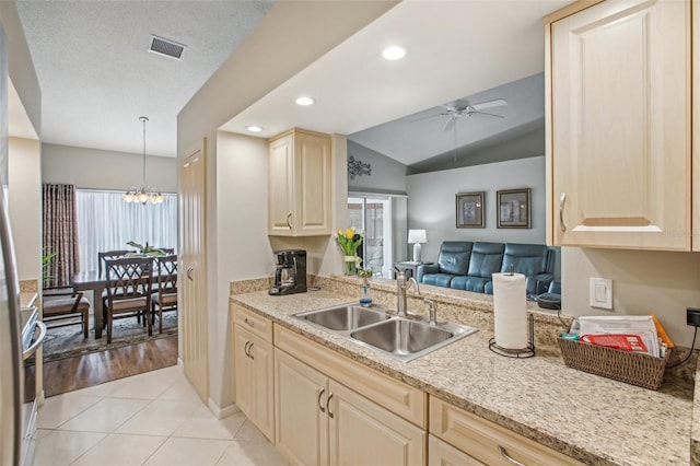 kitchen with light tile patterned floors, lofted ceiling, hanging light fixtures, ceiling fan with notable chandelier, and sink