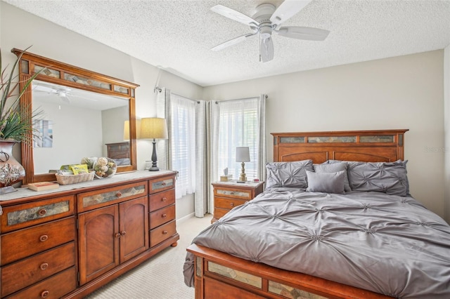 carpeted bedroom with ceiling fan and a textured ceiling