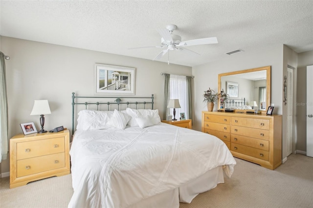 bedroom featuring a textured ceiling, ceiling fan, a closet, and light carpet