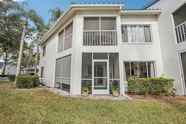 rear view of property with a yard and a sunroom