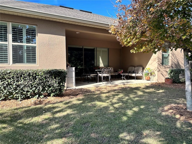 back of property with a yard and a patio