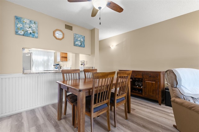 dining room with ceiling fan, light hardwood / wood-style floors, and a textured ceiling