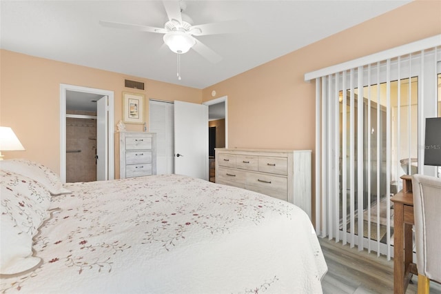 bedroom featuring ceiling fan, a closet, connected bathroom, and light hardwood / wood-style flooring