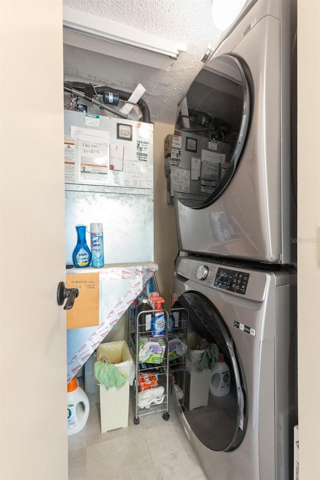 laundry area featuring a textured ceiling, stacked washer and dryer, and light tile patterned flooring