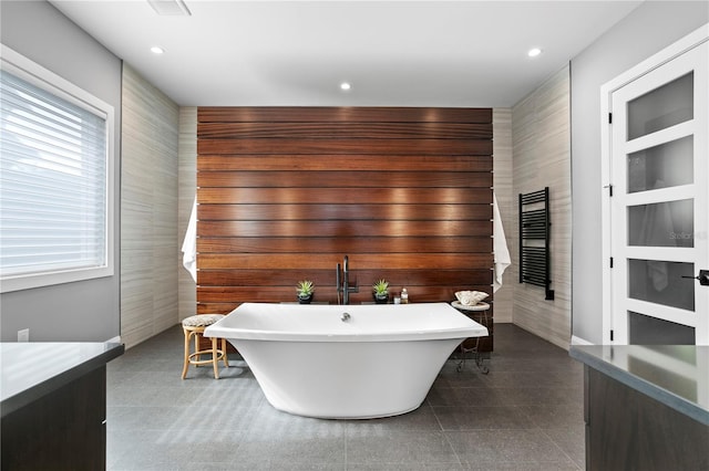 bathroom featuring vanity, tile patterned floors, a bathtub, and tile walls