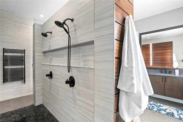 bathroom with a tile shower, radiator, tile patterned flooring, and vanity