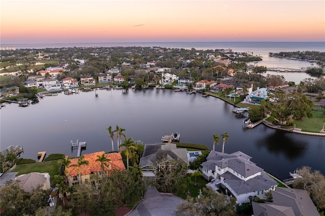 aerial view at dusk featuring a water view