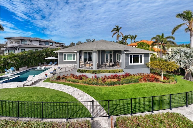 rear view of house with a sunroom, a patio area, a fenced in pool, and a yard