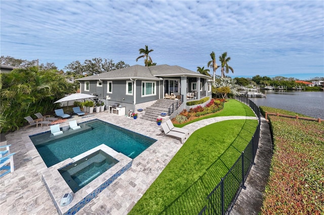 rear view of house with a yard, a water view, a patio, and a pool with hot tub