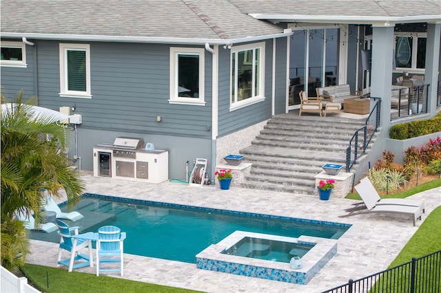 view of pool with an in ground hot tub, an outdoor hangout area, a patio area, and exterior kitchen