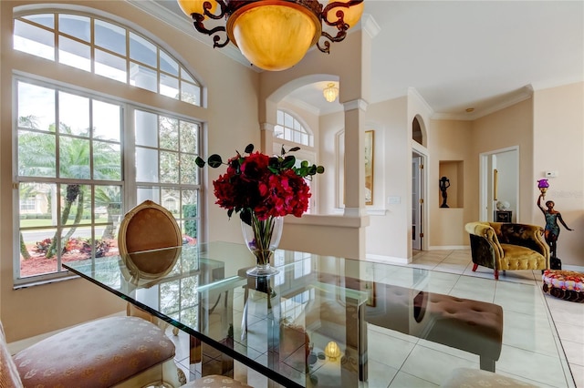 dining space with a chandelier, decorative columns, crown molding, and light tile patterned flooring