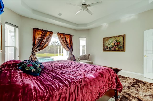 bedroom featuring ceiling fan, light tile patterned flooring, a raised ceiling, and access to outside