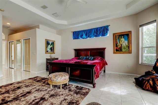 bedroom with a raised ceiling, ceiling fan, and light tile patterned floors