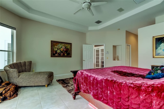 tiled bedroom with ceiling fan and a tray ceiling