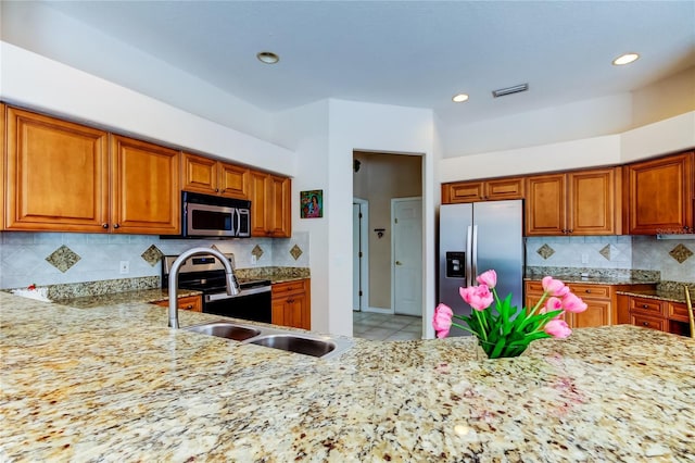 kitchen featuring decorative backsplash, appliances with stainless steel finishes, light stone counters, sink, and light tile patterned floors