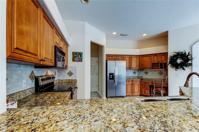 kitchen featuring backsplash, light stone countertops, sink, and stainless steel appliances