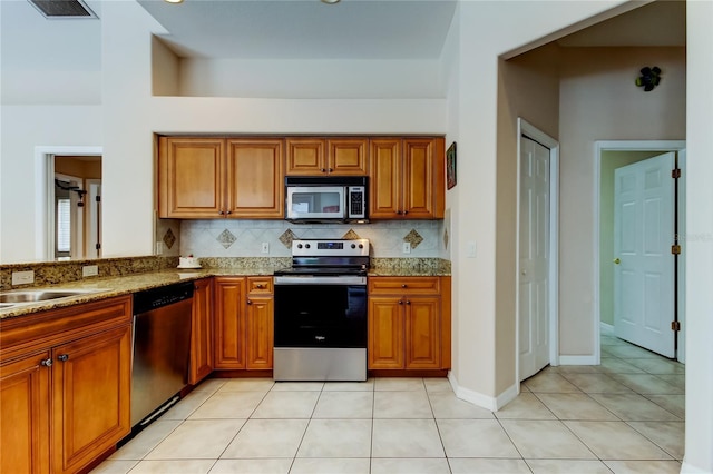 kitchen featuring light stone countertops, appliances with stainless steel finishes, decorative backsplash, sink, and light tile patterned floors