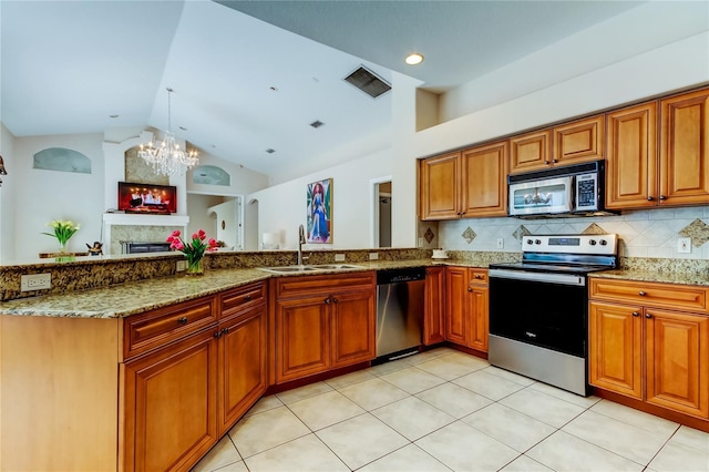 kitchen featuring decorative backsplash, appliances with stainless steel finishes, light stone counters, sink, and an inviting chandelier