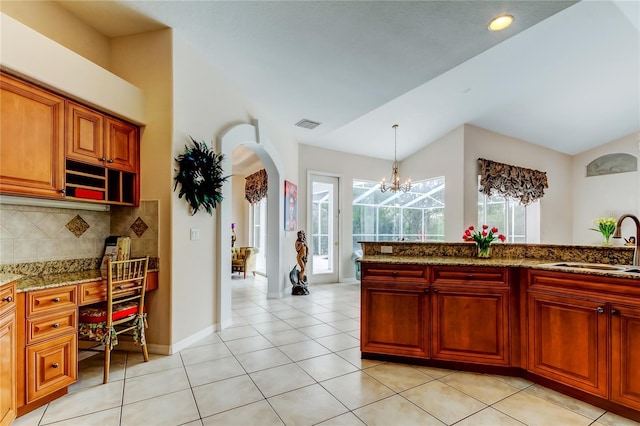 kitchen featuring pendant lighting, backsplash, sink, vaulted ceiling, and a notable chandelier