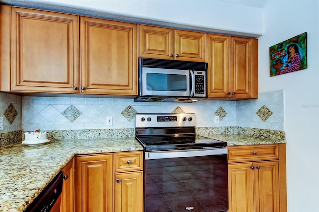 kitchen featuring tasteful backsplash, light stone counters, and appliances with stainless steel finishes