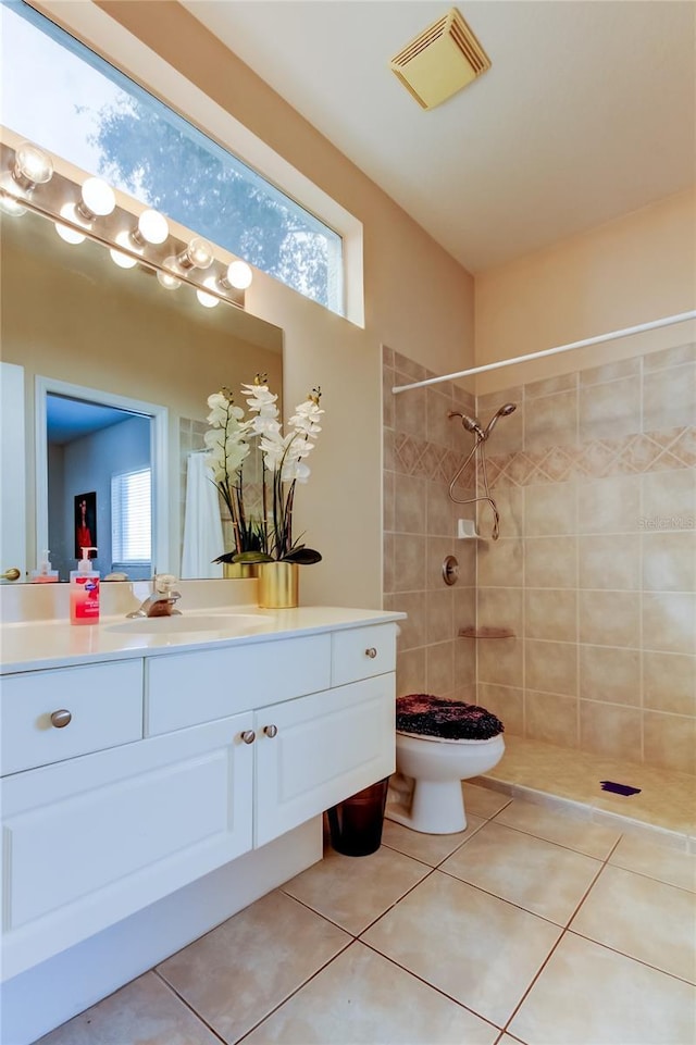 bathroom with toilet, tile patterned flooring, and tiled shower