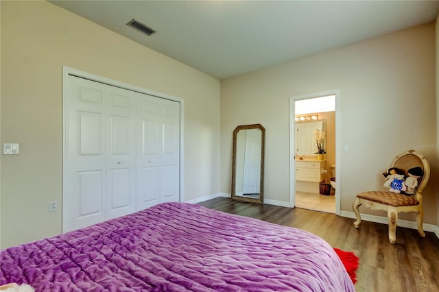 bedroom featuring ensuite bathroom, wood-type flooring, and a closet