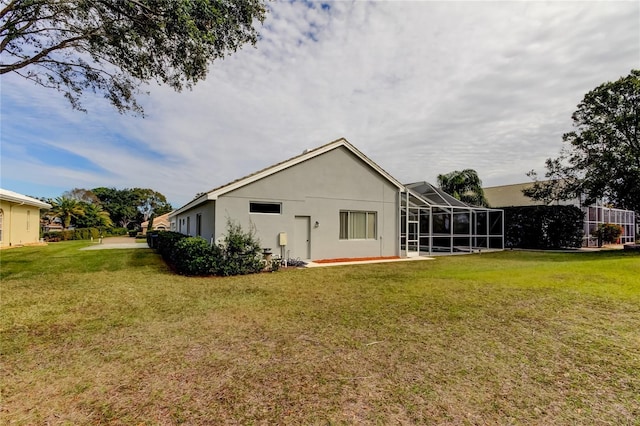 rear view of property featuring a lawn and glass enclosure