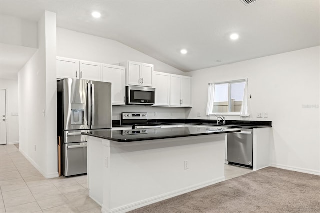 kitchen featuring light tile patterned floors, stainless steel appliances, lofted ceiling, a kitchen island, and white cabinets