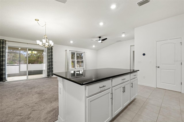 kitchen featuring ceiling fan with notable chandelier, a center island, white cabinetry, light carpet, and vaulted ceiling